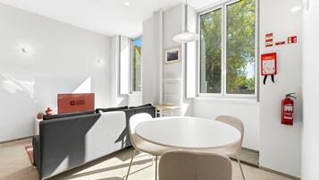 Una habitación moderna con sofá, una mesa redonda y ventana con vista a árboles.