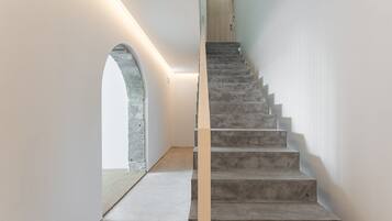 Una escalera con barandilla de madera y una pared de piedra a un lado.