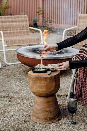 An outdoor dining area with a round table, chairs, and a fire pit. - Salted Sun with pool, spa & fire pit (Manyana)