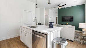 A modern kitchen with a dishwasher, a sink, and a ceiling fan. - Landing | Beautiful 2BD, Gym (Palmetto)
