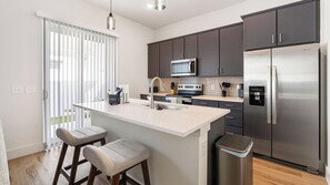 Cozinha moderna com ilha central, eletrodomésticos de aço inoxidável e vista para o exterior.