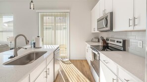 A modern kitchen with a stainless steel sink, a microwave, an oven, and a toaster. - Landing | Stylish 2BD, Gym (Palmetto)