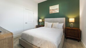 A bedroom with a bed, two bedside tables, a nightstand, a door, and a painting on the wall. - Landing | Stylish 2BD, Gym (Palmetto)