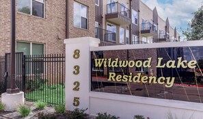 A residential building with a sign reading 'Wildwood Lake Residency' and a number '8325' on a white pillar. - Landing | Stylish 2BD, Gym, Pool (Mission Bend)