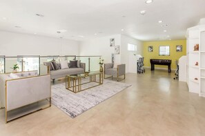 A modern living room with a sofa, armchair, and coffee table, a yellow accent wall, and a glass railing. - Landing | Stylish 2BD, Gym, Pool (Mission Bend)