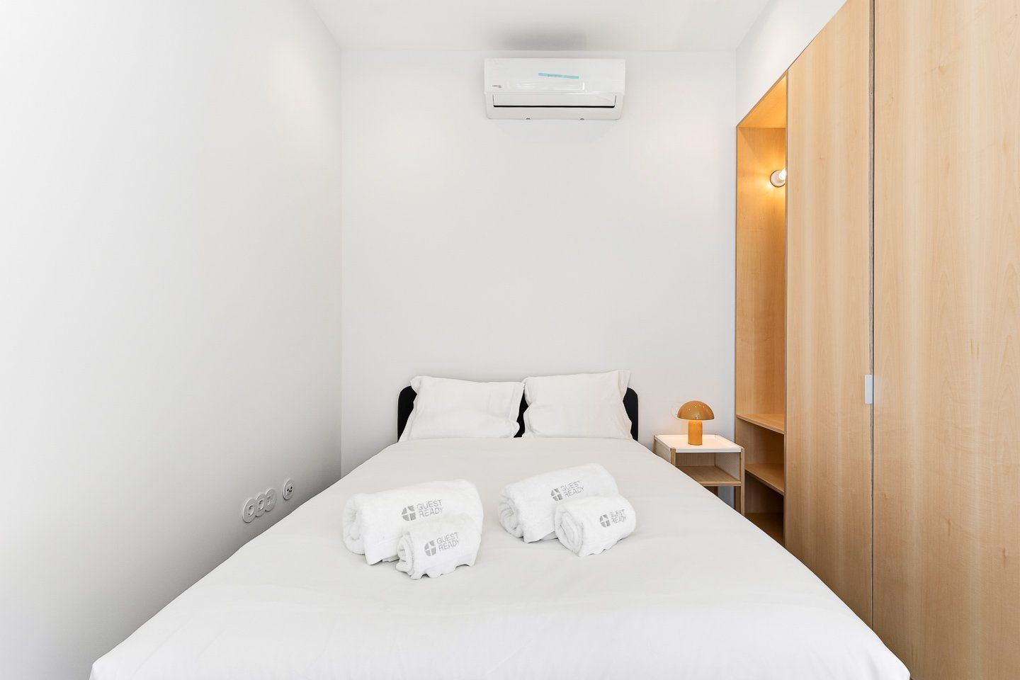 Une chambre d’hôtel équipée d’un lit, d’une table de chevet, d’une lampe, d’une armoire et d’un appareil de climatisation.