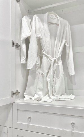 A white robe hanging on a white cabinet with drawers.