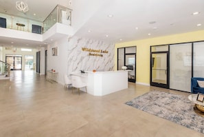 A spacious lobby with a reception desk, a high ceiling with recessed lighting, and a view of the outside. - Landing | Incredible 2BD, Pool, Gym (Mission Bend)
