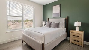 A bedroom with a bed, bedside tables, and a view through the window. - Landing | Incredible 2BD, Pool, Gym (Mission Bend)