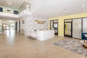 A spacious lobby with a reception desk, a high ceiling with recessed lighting, and a view of the outside. - Landing | Modern 2BD, Pool, Gym (Mission Bend)