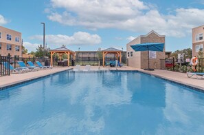 A swimming pool with lounge chairs and a covered seating area. - Landing | Chic 2BD, Gym, Pool (Mission Bend)