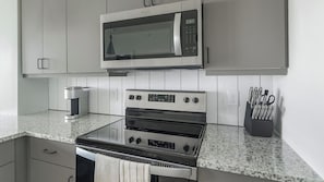 A kitchen with a microwave, oven, and coffee maker. - Landing | Modern 1BD in Sunnyside (Houston)