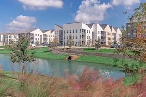 A modern apartment complex with a landscaped area including a pond and a small bridge. - Landing | Spectacular 1BD in Sunnyside (Houston)