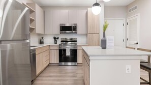 A modern kitchen with stainless steel appliances, wooden cabinets, and a central island. - Landing | Incredible 1BD in Loughman (Davenport)