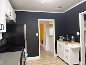 A kitchen with white cabinets, a black refrigerator, and a wooden countertop with a coffee maker. - Colorful 3 BDRM home w/ pool (Henderson)