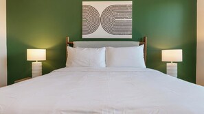 A hotel room with a bed, two bedside lamps, and a wall art piece above the bed. - Landing | Stylish 2BD in Loughman (Davenport)