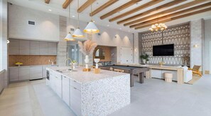 A modern kitchen with a large island, pendant lighting, and a built-in TV. - Landing | Chic 2BD in Loughman (Davenport)