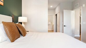 A hotel room with a bed, a nightstand, a lamp, and a view of the hallway. - Landing | Spectacular 2BD in Loughman (Davenport)
