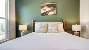 A neatly made bed with two pillows, a wall-mounted painting, and two bedside lamps. - Landing | Amazing 2BD in Loughman (Davenport)