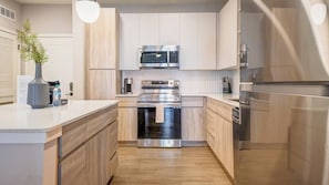 A modern kitchen with stainless steel appliances, wooden cabinetry, and a central island. - Landing | Amazing 2BD in Loughman (Davenport)