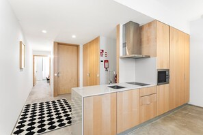 Eine moderne Küche mit Holzschränken, einer Edelstahl-Spüle und einer Mikrowelle.