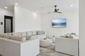 A modern living room with a sofa, two armchairs, a coffee table, and a ceiling fan. - Landing | Amazing 1BD, Pool, Clubhouse (Sarasota)