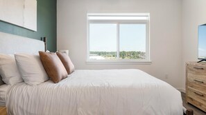 A bedroom with a bed, pillows, a dresser, and a window with a view. - Landing | Spectacular 1BD in North Kissimmee (Kissimmee)
