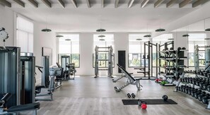 A spacious gym with various exercise equipment, large windows, and a high ceiling. - Landing | Amazing 2BD in North Kissimmee (Kissimmee)