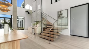 A modern interior with a staircase, a dining area, and a view through glass doors. - Landing | Incredible 2BD in North Kissimmee (Kissimmee)