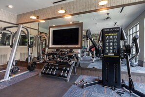 Un gimnasio con diversos equipos de ejercicio, como pesas, una cinta de correr y una bicicleta estática.