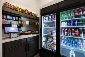 A self-service kiosk with a digital screen and a refrigerated display case stocked with beverages and snacks. - Landing | Incredible 2BD, Courtyard (Garland)