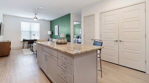 Una cocina moderna con encimera de granito, armarios de madera y un comedor con mesa y sillas.