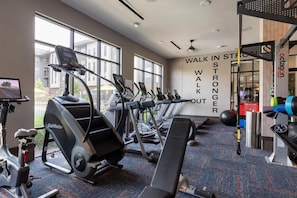 A gym with treadmills, a stair climber, and a wall with motivational text. - Landing | Chic 2BD, Courtyard (Garland)