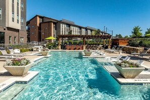 A rectangular pool with clear blue water, surrounded by lounge chairs and planters. - Landing | Spectacular 1BD, Courtyard (Garland)
