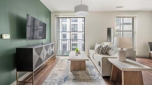 A modern living room with a sofa, coffee table, and a TV mounted on the wall. - Landing | Beautiful 1BD, Gym (Birmingham)