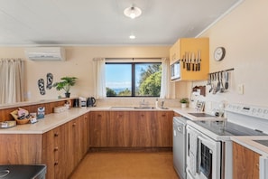 A compact kitchen with wooden cabinets, a built-in oven, and a window with a view. - Koromiko Rest - Omori *pet friendly* (Omori)