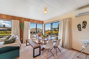 A modern hotel room with a large window, a dining table, a sofa, and a small table with chairs. - Koromiko Rest - Omori *pet friendly* (Omori)