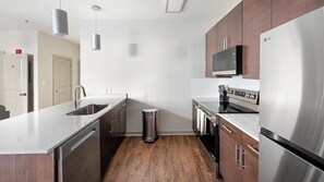 A modern kitchen with stainless steel appliances, wooden cabinets, and a stainless steel sink. - Landing | Spectacular 1BD, Gym (Birmingham)