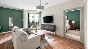 A modern living room with a sofa, coffee table, and a TV mounted on the wall. - Landing | Spectacular 1BD, Gym (Birmingham)