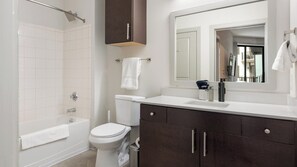 Un baño moderno con bañera, inodoro y tocador con espejo.