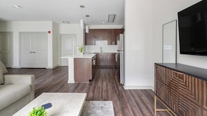 A modern kitchen with dark wood cabinets, a central island, and a built-in oven. - Landing | Stunning 1BD, Gym (Birmingham)