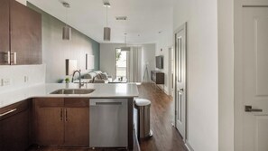 A modern kitchen with a central island, stainless steel appliances, and a view to the living area. - Landing | Beautiful 1BD, Gym (Birmingham)