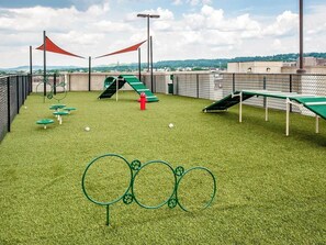 A rooftop playground with artificial grass, play structures, and a view of the cityscape. - Landing | Beautiful 1BD, Gym (Birmingham)