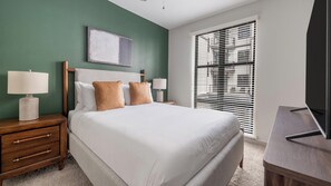 A hotel room with a bed, bedside tables, a lamp, a painting on the wall, and a window with blinds. - Landing | Incredible 1BD, Gym (Birmingham)