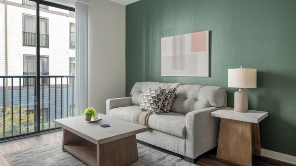 A modern living room with a sofa, a coffee table, a lamp, and a painting on the wall. - Landing | Incredible 1BD, Gym (Birmingham)