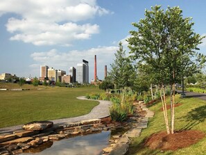 A landscaped area with a curved pathway, a small pond, and a tree. - Landing | Stunning 1BD, Gym (Birmingham)