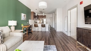 A modern living room with a sofa, coffee table, and a TV. - Landing | Amazing 1BD, Gym (Birmingham)