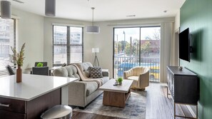 A modern living room with a sofa, coffee table, and a TV on a stand. - Landing | Stunning 2BD, Gym (Birmingham)