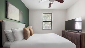 A hotel room with a bed, a television, a window with blinds, and a ceiling fan. - Landing | Modern 2BD, Gym (Birmingham)
