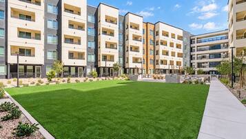 Un immeuble d’appartements moderne doté de nombreux balcons, d’une pelouse bien entretenue et offrant une vue sur un ciel dégagé.